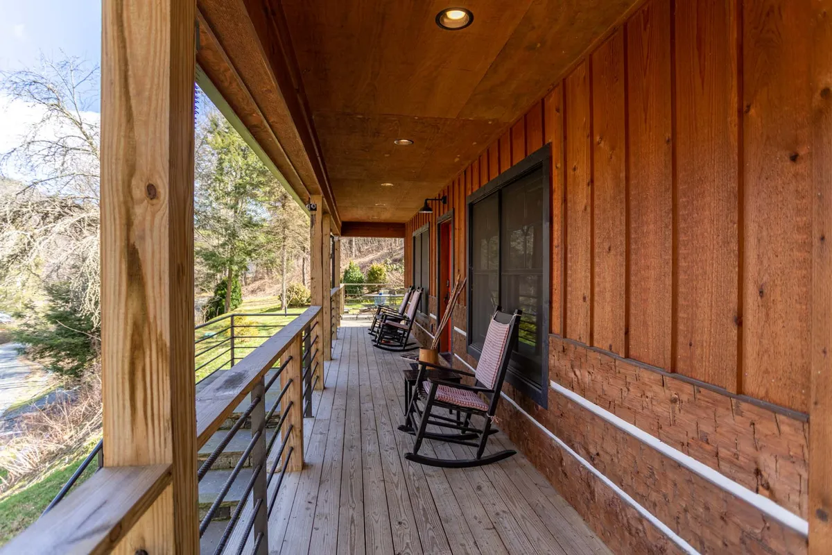 A close-up of two wooden rocking chairs on a cozy porch, framed by a rustic railing and the cabin's exterior wall. The peaceful setting is perfect for unwinding after outdoor adventures.
